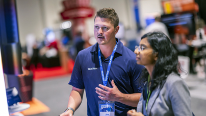 Two professionals discussing industrial technology at a Reliable Plant exhibition booth.